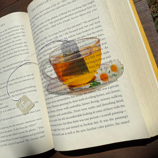 Open book with a transparent cup of tea and cookies on top